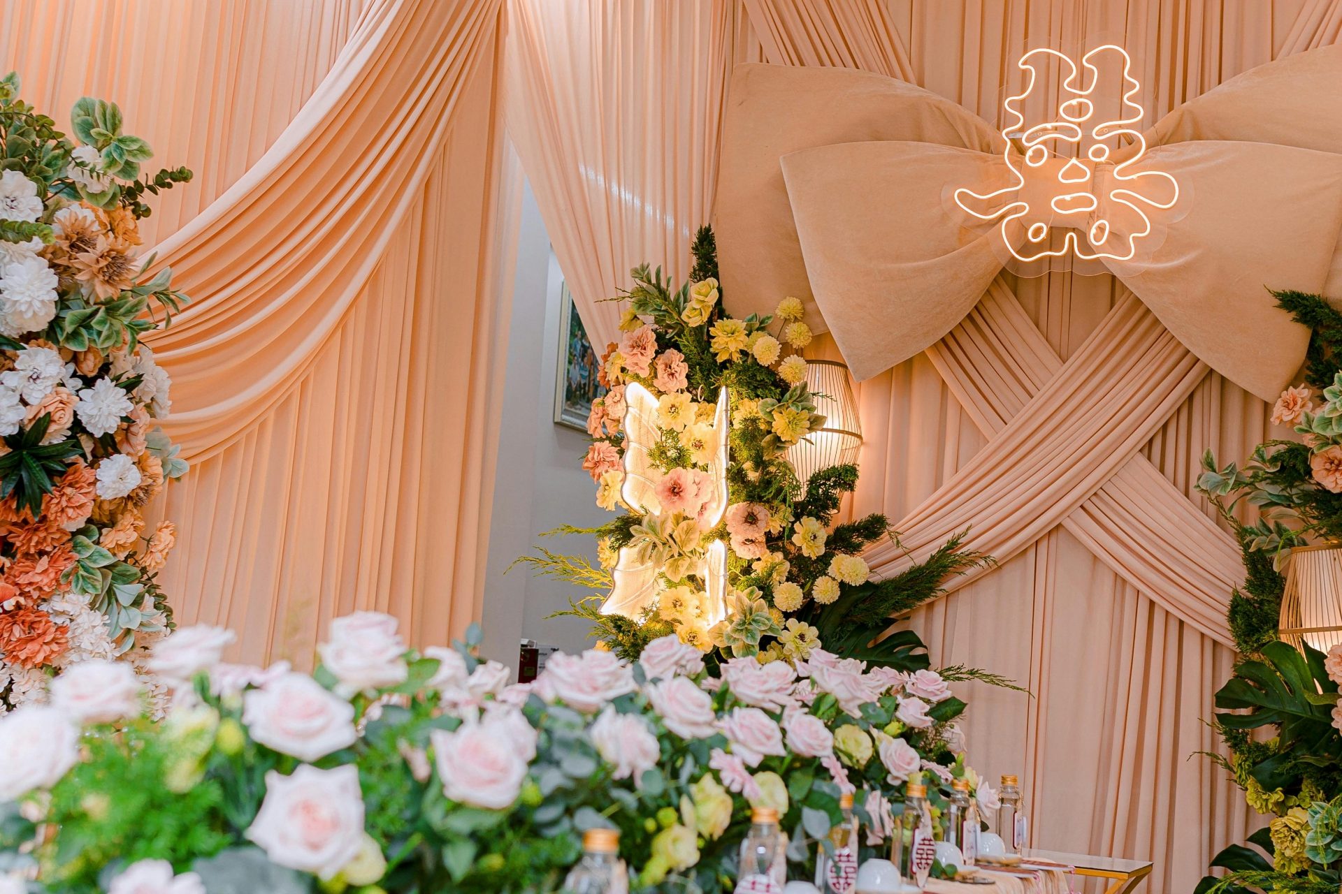 Décoration de mariage élégante avec de somptueuses compositions florales et un symbole néon lumineux.